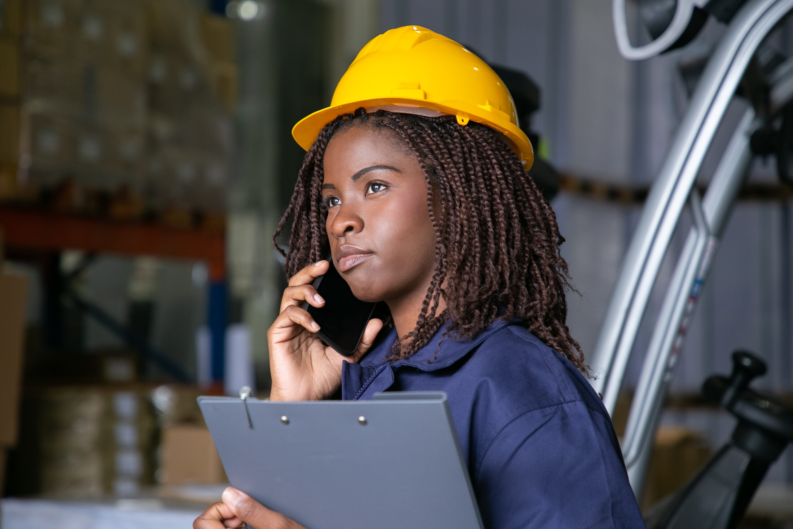 pensive black female engineer hardhat standing warehouse talking cellphone shelves with goods background copy space labor communication concept scaled
